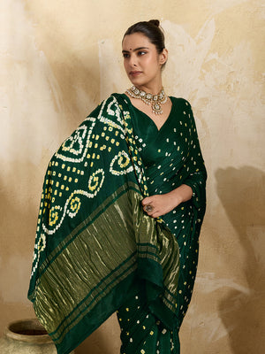 A bottle green saree with bandhani print and lagdi patola pallu, alongside a blouse piece.