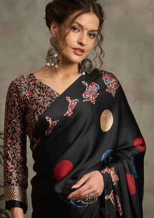 A black silk saree with red and blue ajrak print design and a golden border.