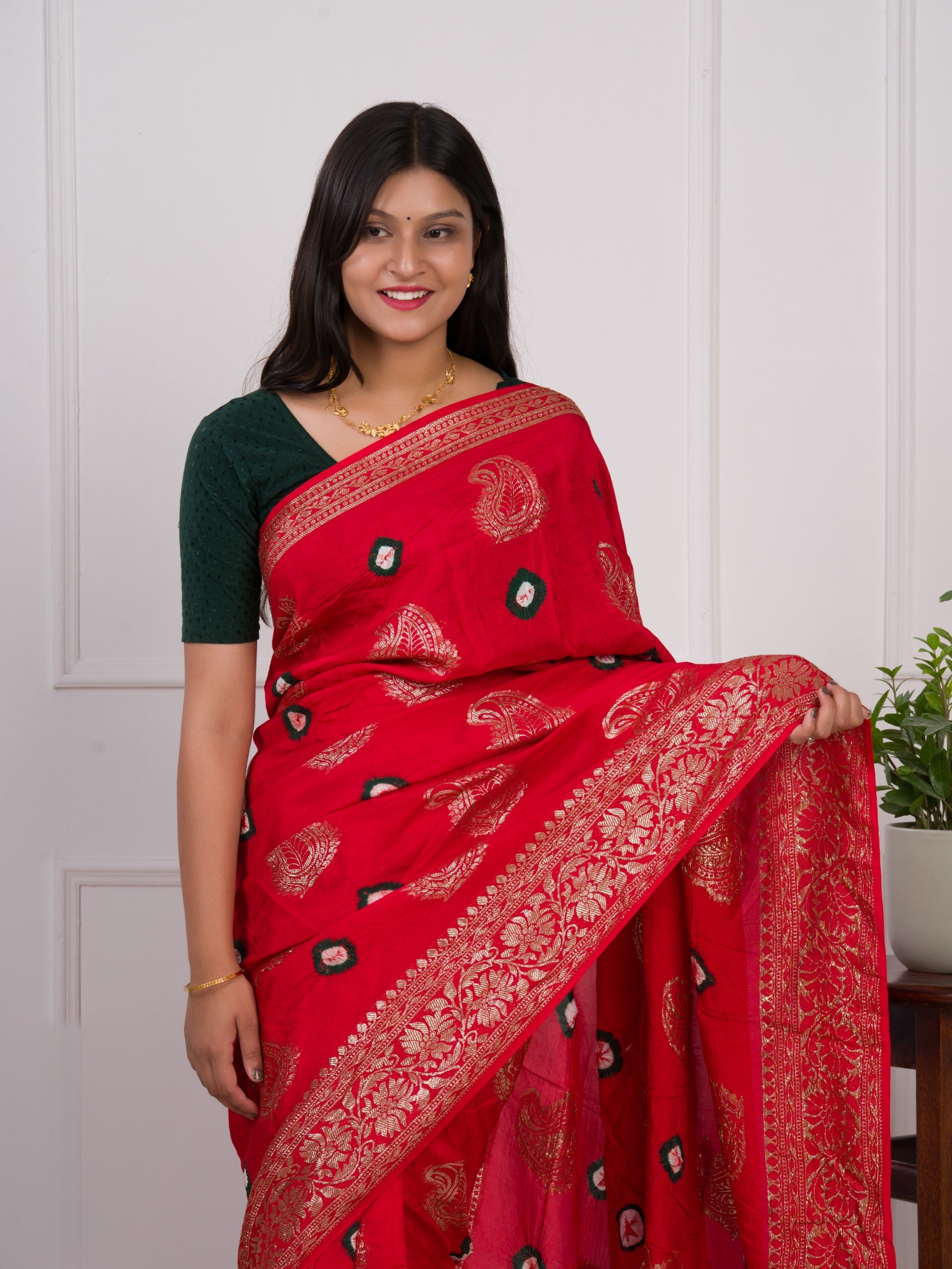A red saree with green patterns with Dola Silk Bandhani Zari Weaving Work